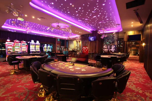 Um homem concentrado em seu laptop com estatísticas ao vivo ao fundo, destacando os recursos dedicados de esportes e jogos do app móvel 61T.